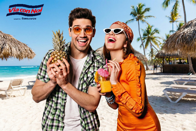 Due persone sorridenti in vacanza con cocktail in mano